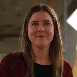 A smiling woman in a maroon cardigan and black top.