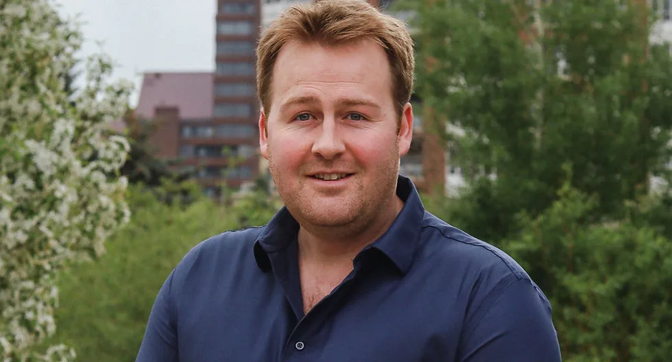 A smiling man in a blue shirt outdoors.