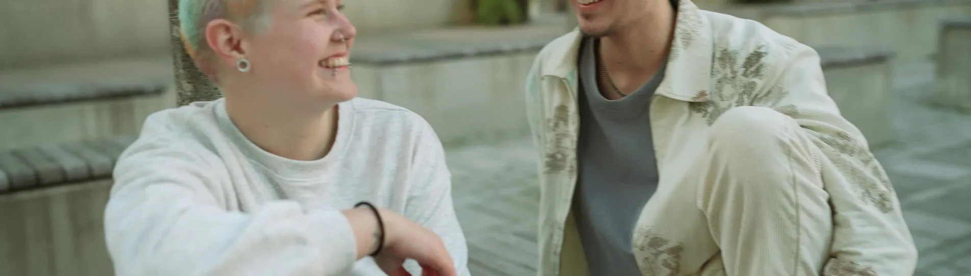 Two young adults laughing during an outdoor conversation.
