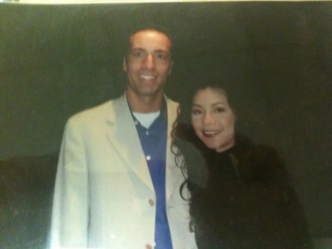 Man and woman smiling together in a dimly lit setting.
