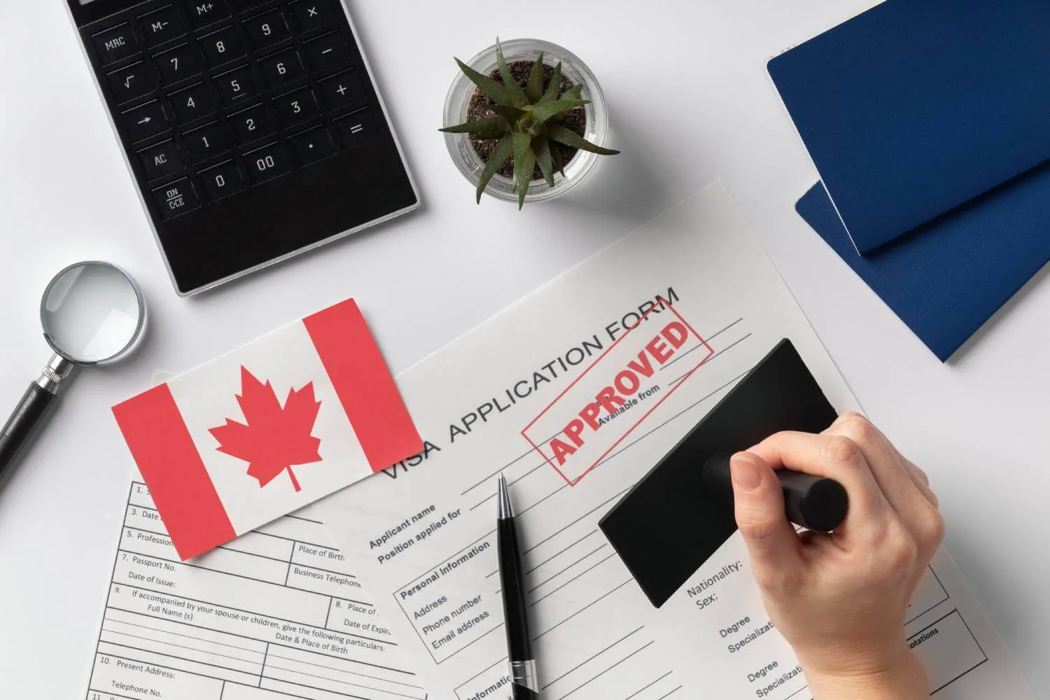 A hand stamping an approved visa application with a Canadian flag.