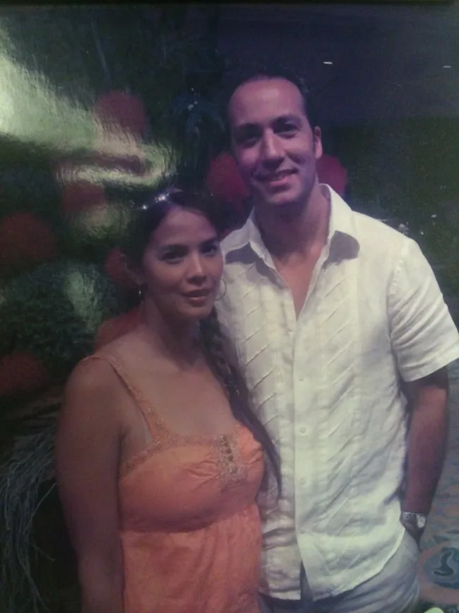 A couple posing together in a dimly lit setting.
