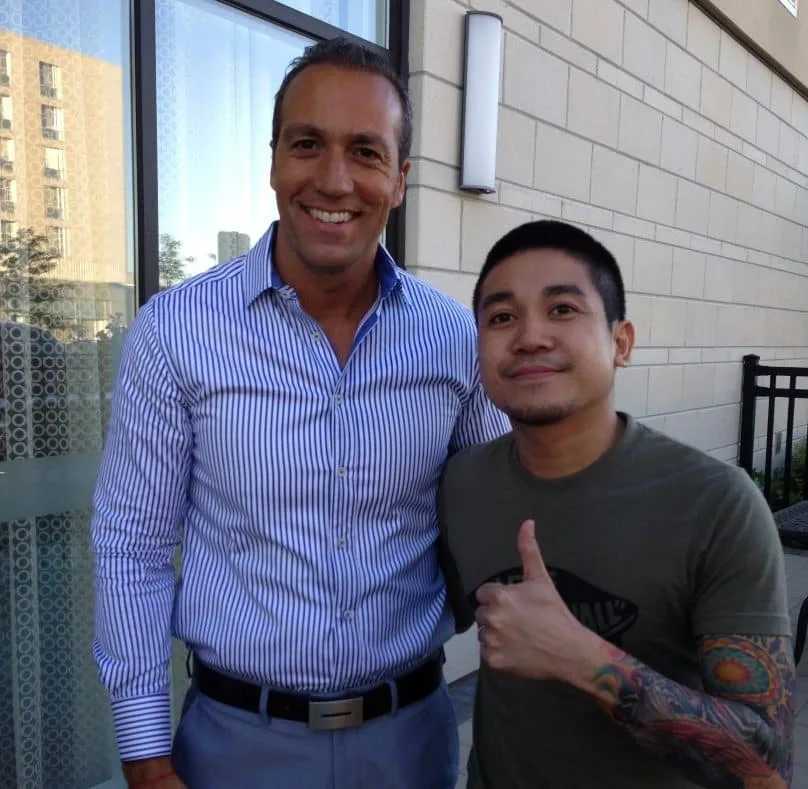 Two men posing together outside a building.