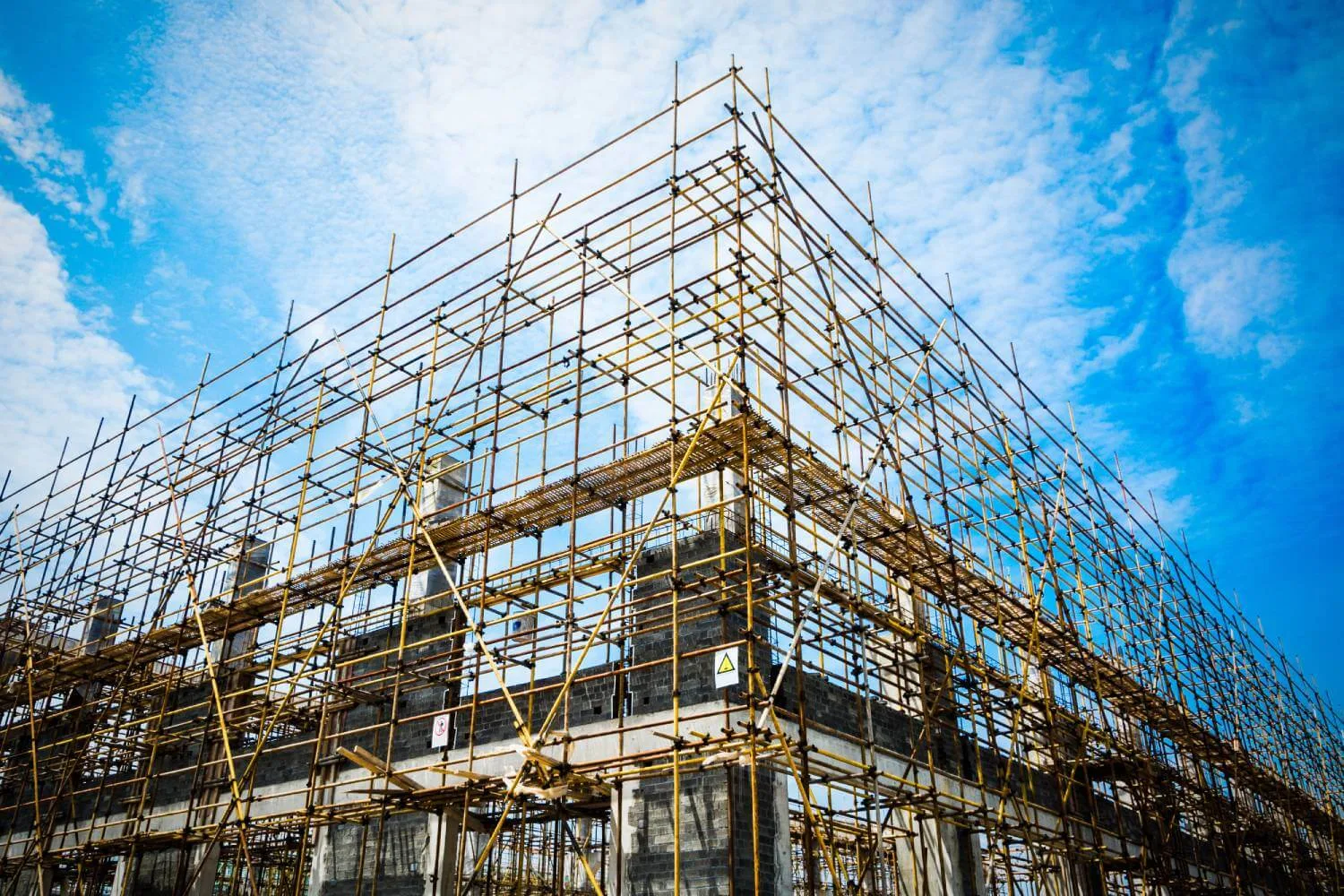 A construction site with extensive scaffolding and a blue sky.