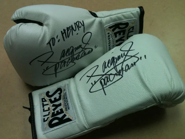 A pair of signed white boxing gloves with inscriptions.