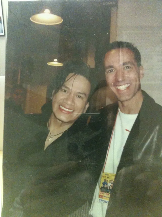 Two men smiling together in a casual setting.