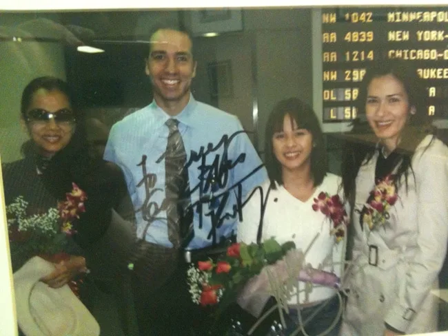 A group photo of four smiling individuals holding flowers.