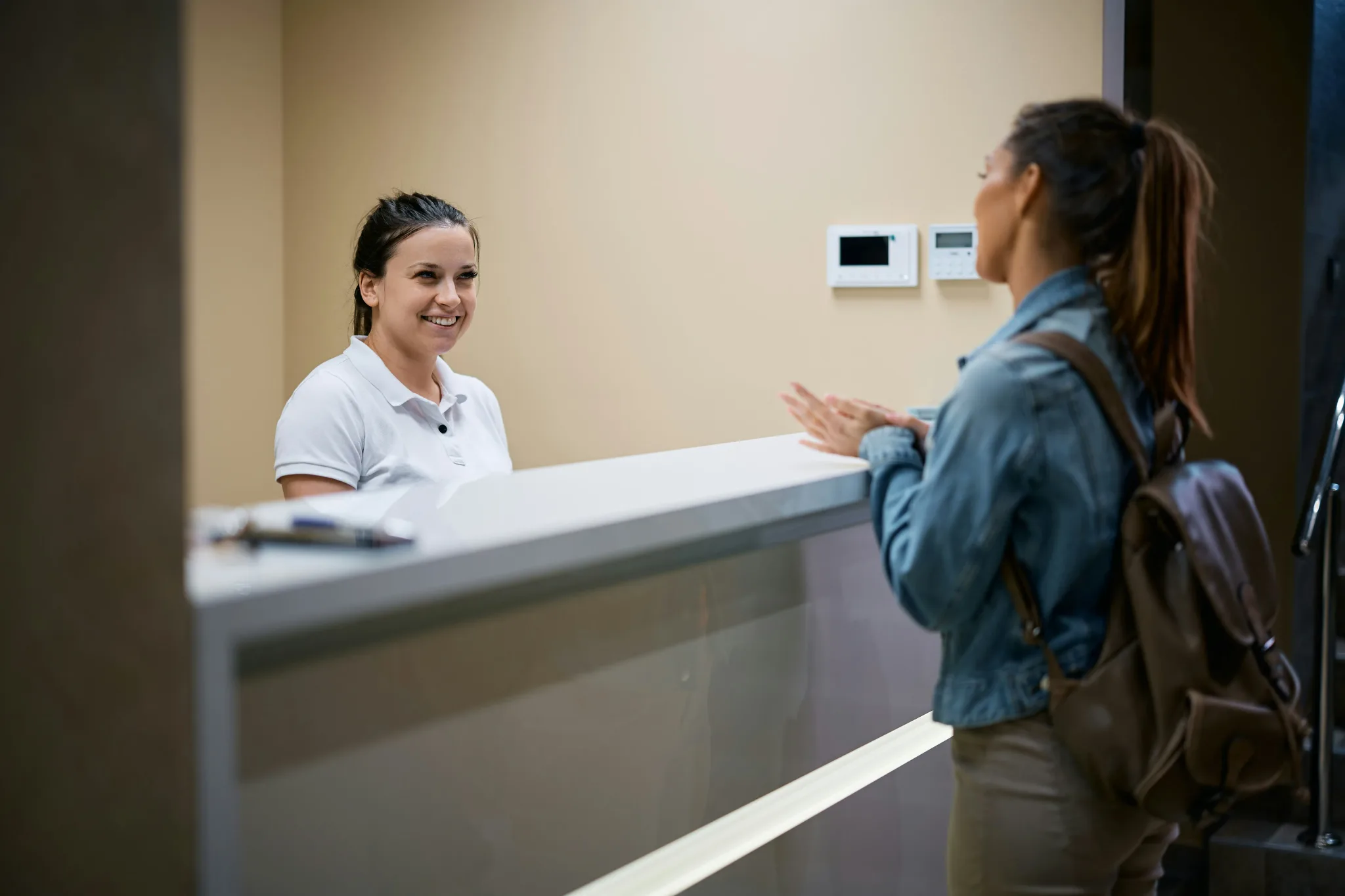 A dental receptionist engaging with a visitor at the front desk.