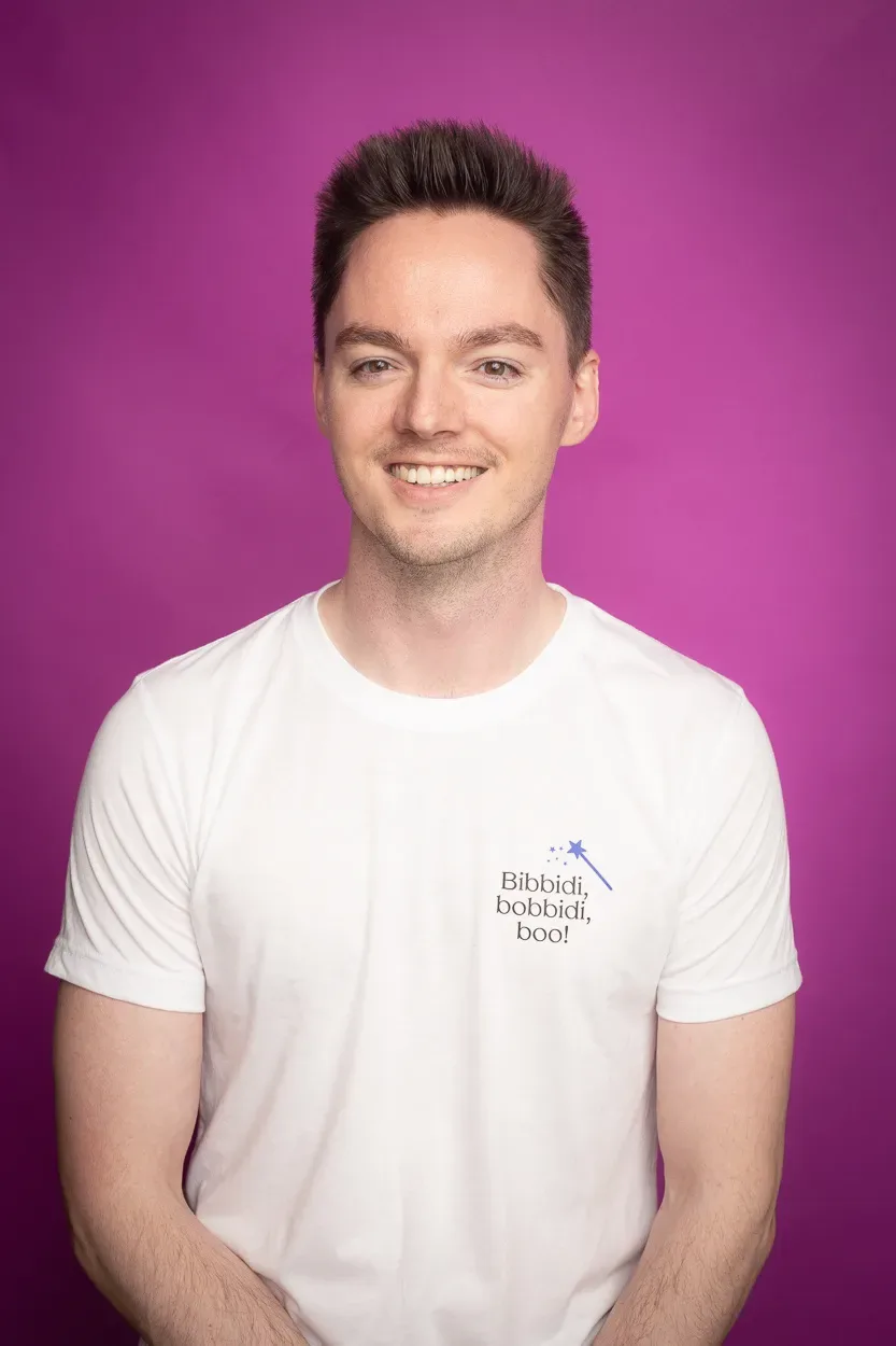 A smiling man in a white t-shirt with a playful phrase.