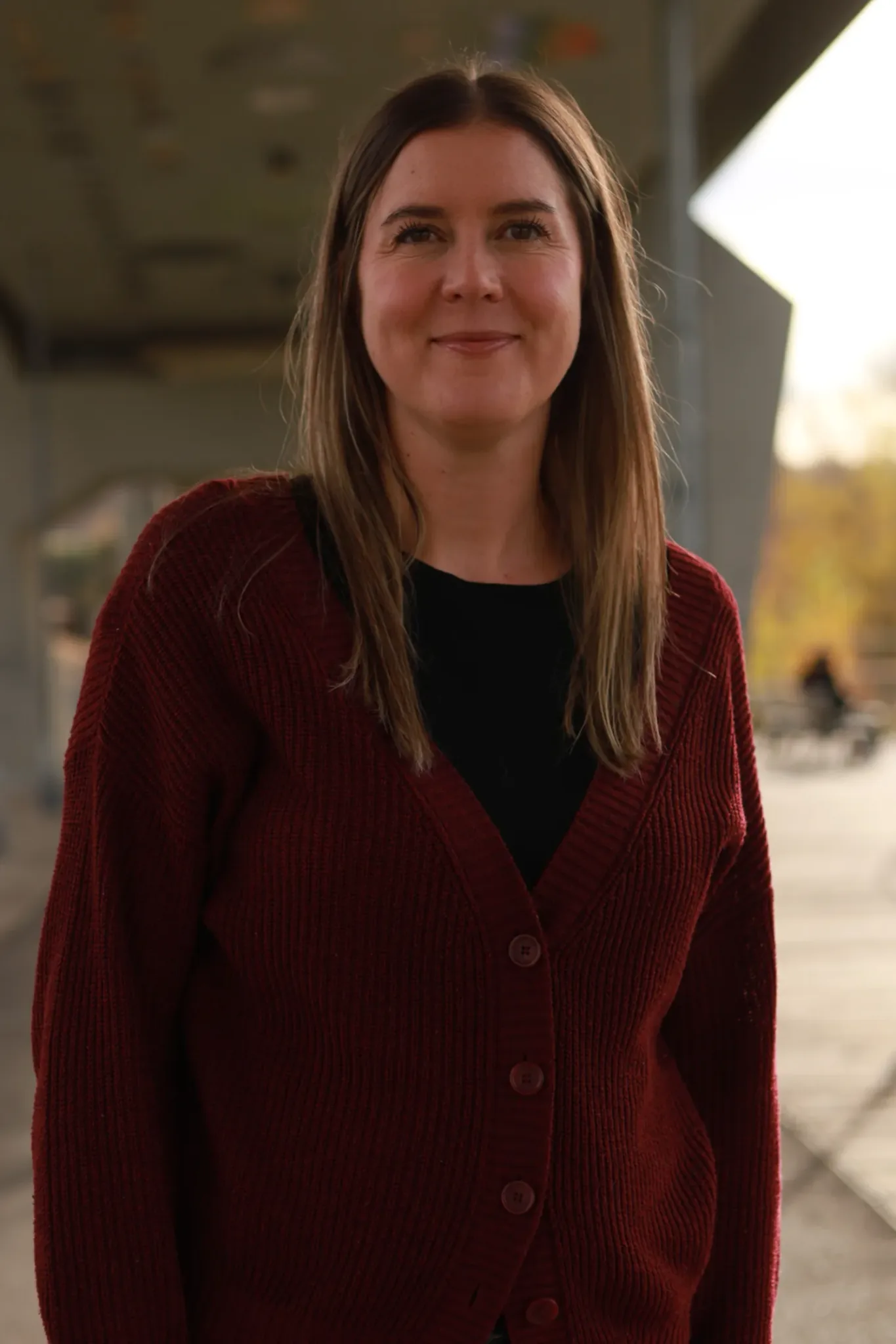 A woman with long hair in a burgundy cardigan.