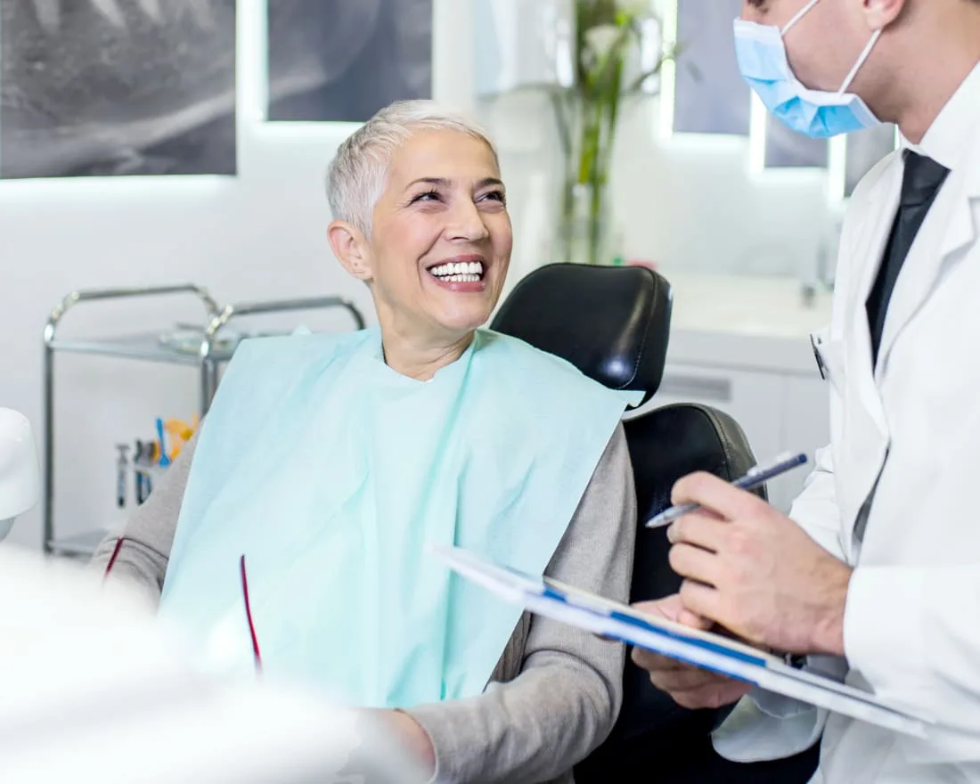 A woman smiles while talking to her dentist in a dental office.