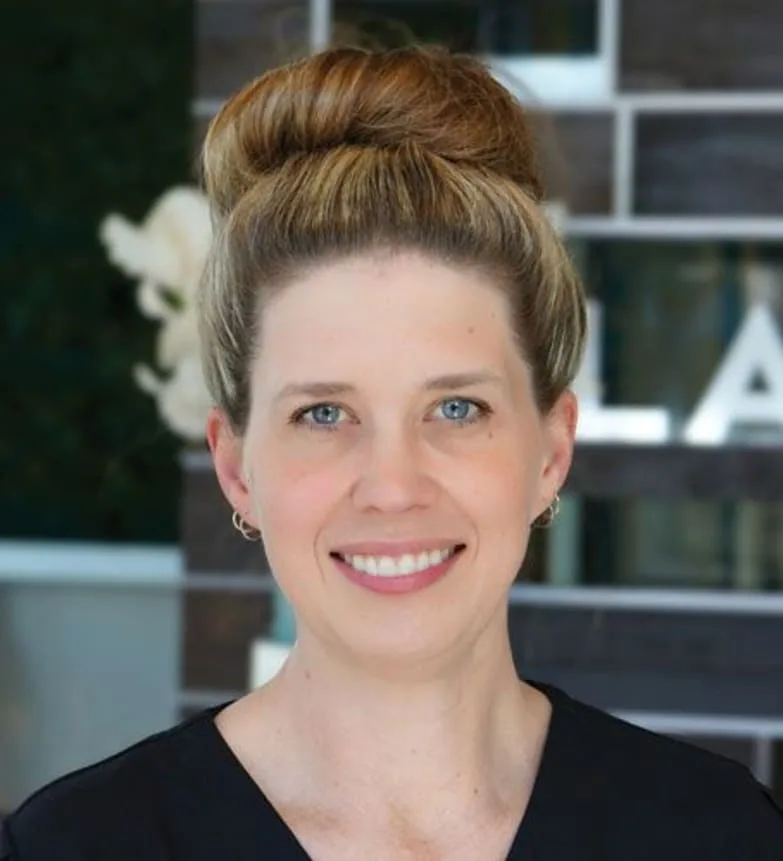 A smiling female dentist in black scrubs.