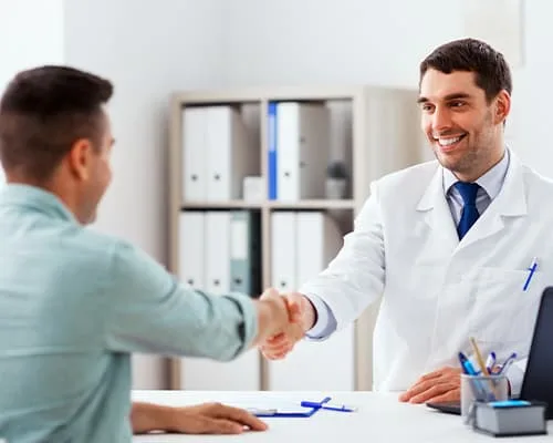 A dentist and patient shaking hands in an office.