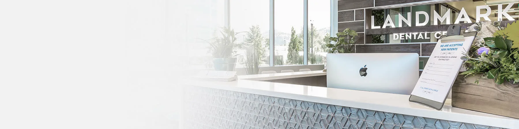 A modern dental reception area with greenery and digital signage.