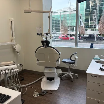 A dental treatment room with a modern chair and city view.