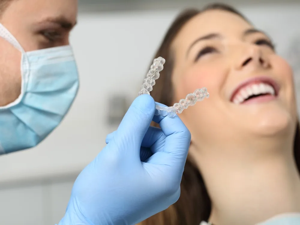 Dental professional showing clear aligner to smiling patient.