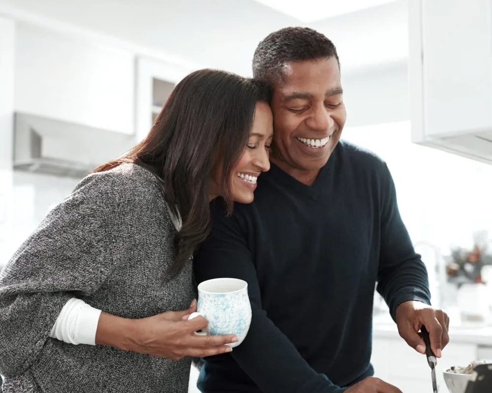 A couple happily cooking together in a modern kitchen.