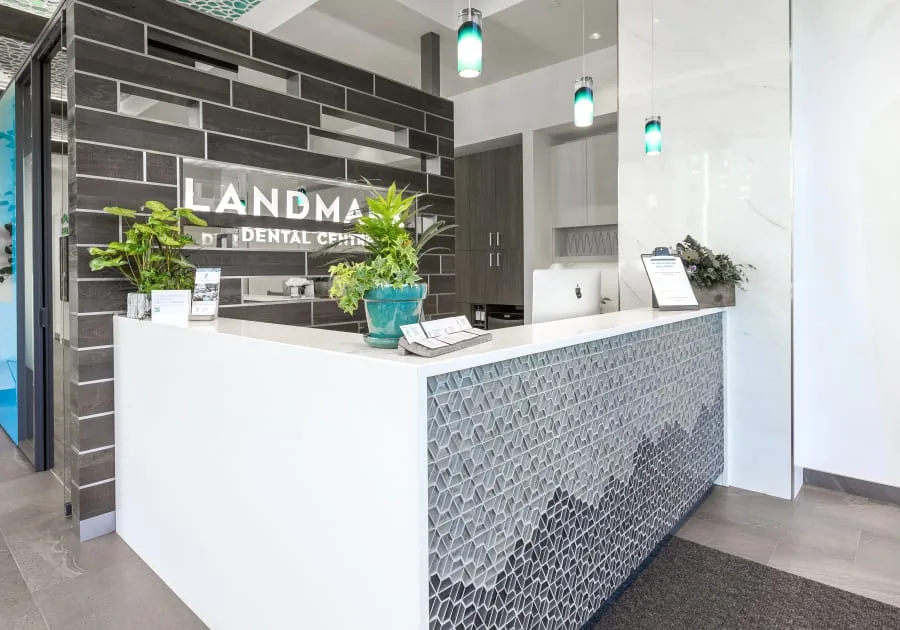 A modern dental reception area with plants and a welcoming desk.