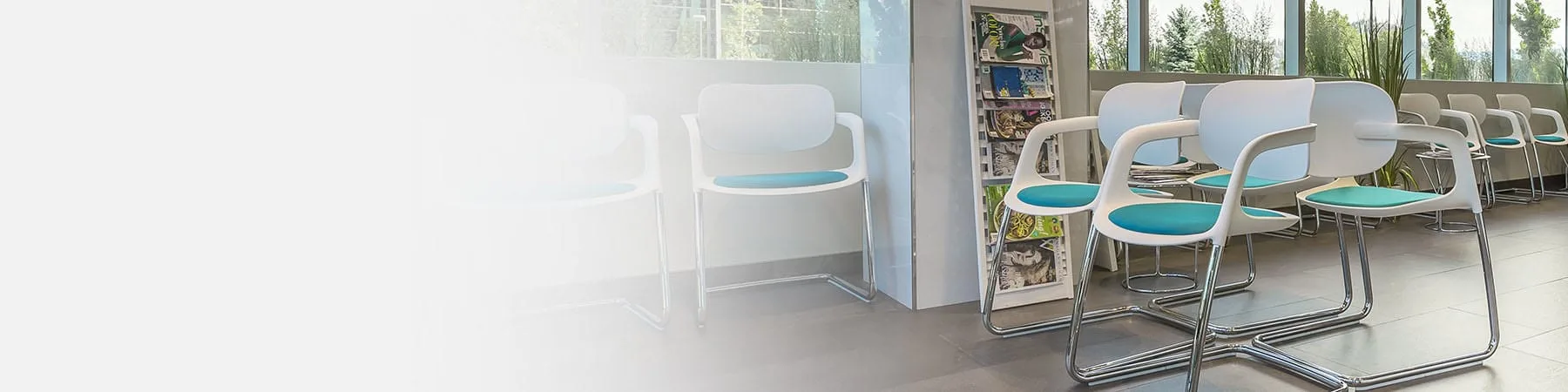 Modern dental waiting area with white chairs and magazines.