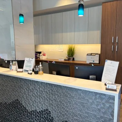 A modern dental reception area with a geometric front desk.