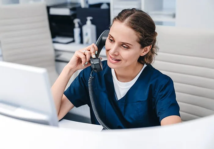 A dental receptionist on the phone at her desk.