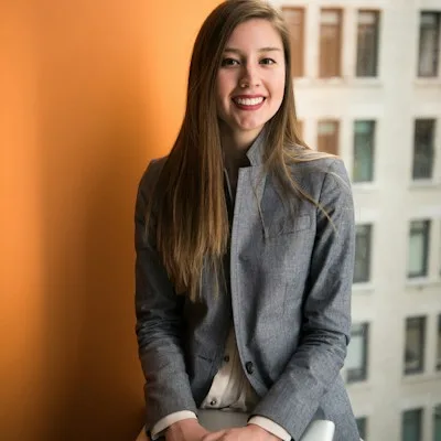 Wendy P., certified dental assistant, seated against an orange wall.