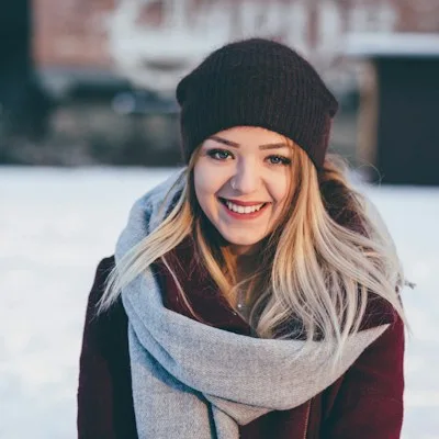 A young woman smiling in a snowy outdoor setting.