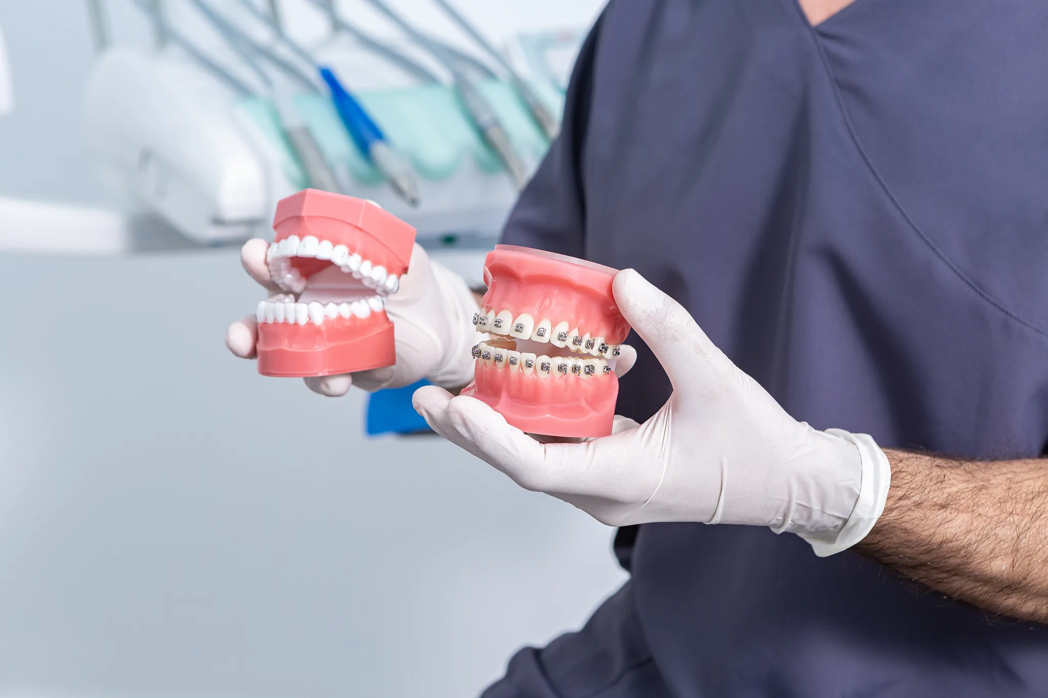 A dental professional showing tooth models with braces and dentures.
