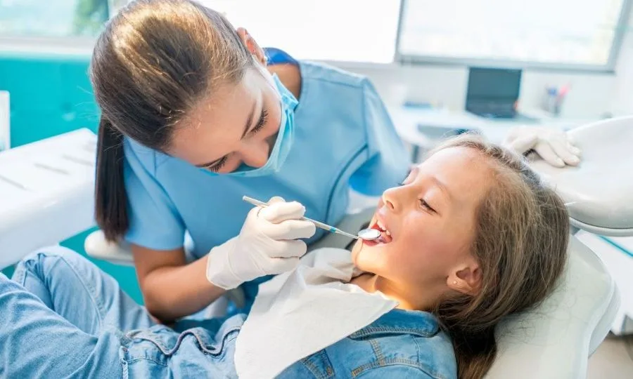 Dentist treating a young patient in a dental chair.