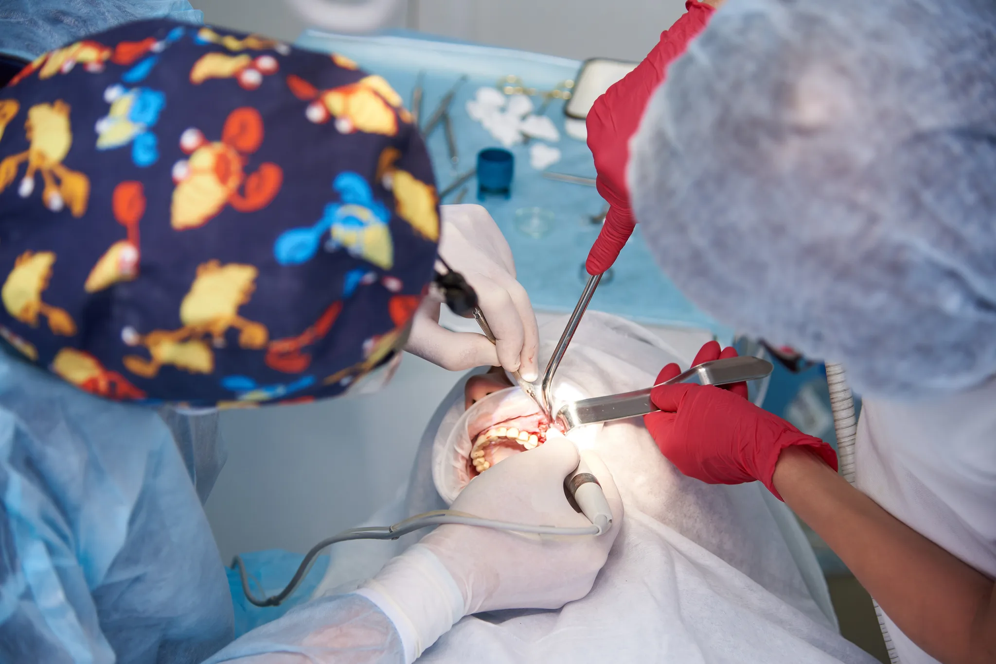 Dental surgery in progress with two clinicians and a patient.