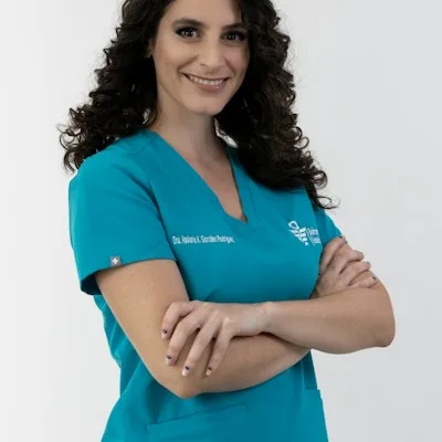 A dental team member in teal scrubs with arms crossed.