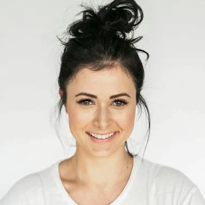 Mihaela B., registered dental hygienist, smiling in a white top.