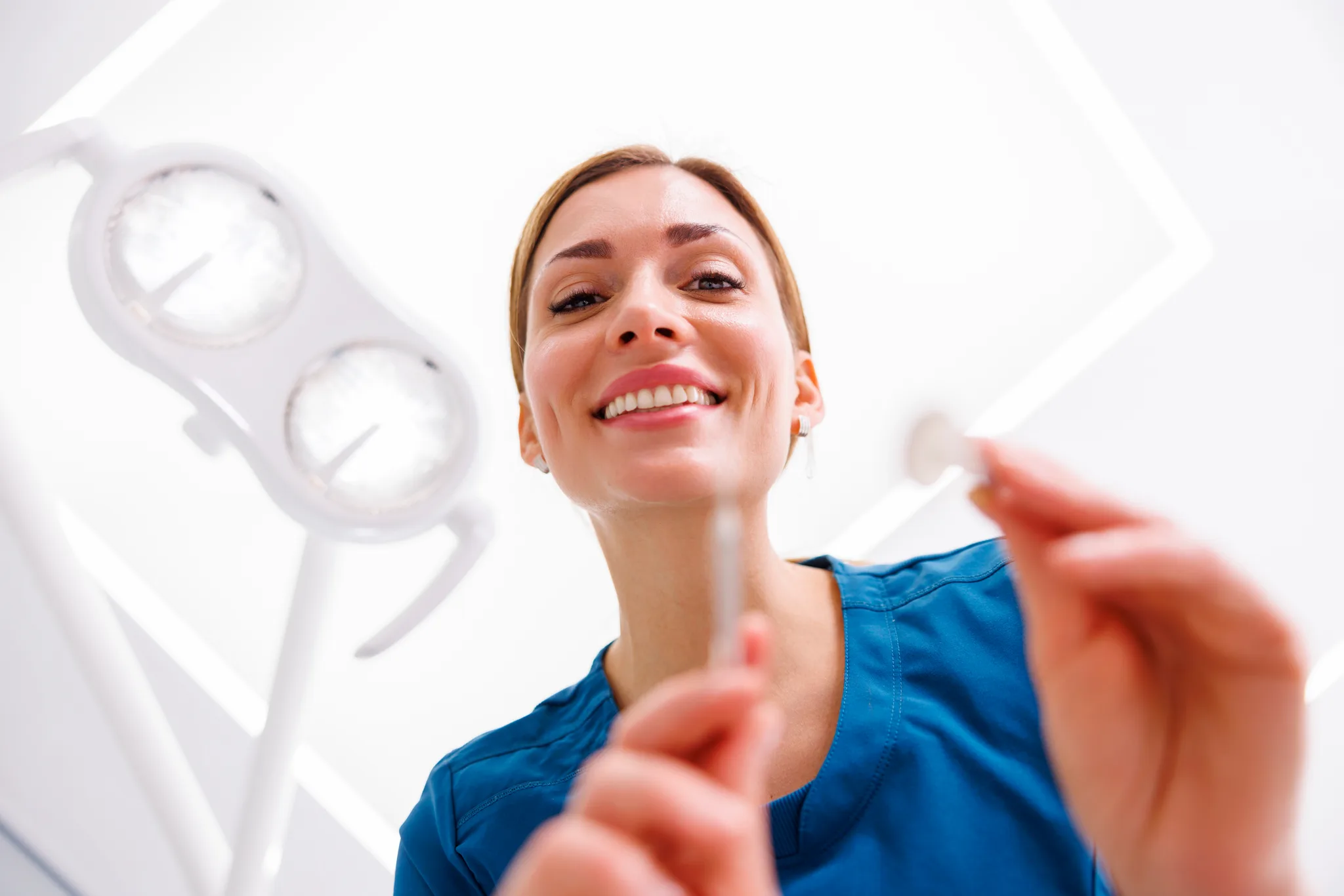 A dentist smiling while checking a patient's teeth.