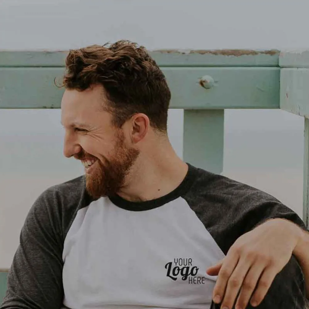 Man smiling in casual shirt by the beach.
