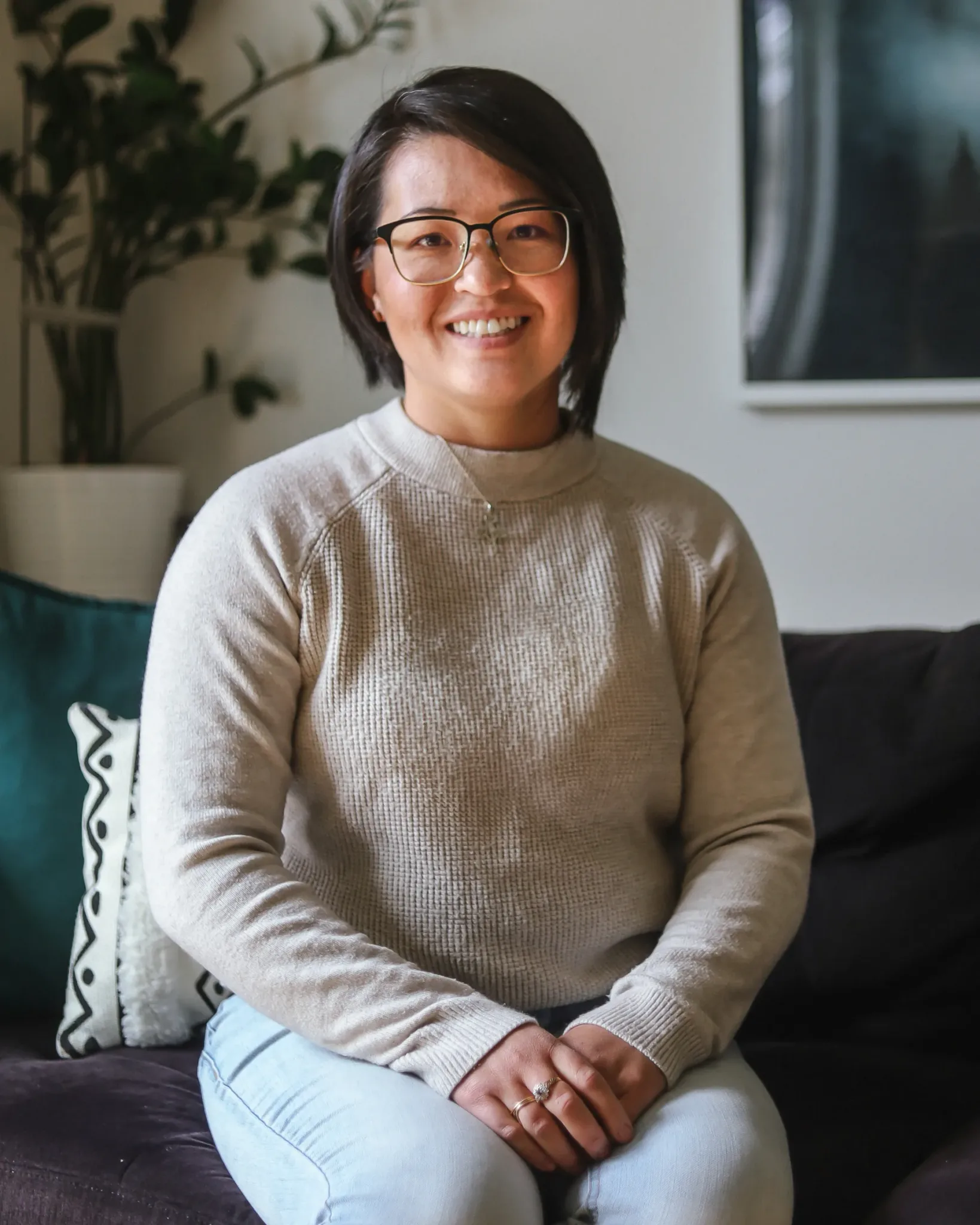 A woman smiling while sitting on a sofa.