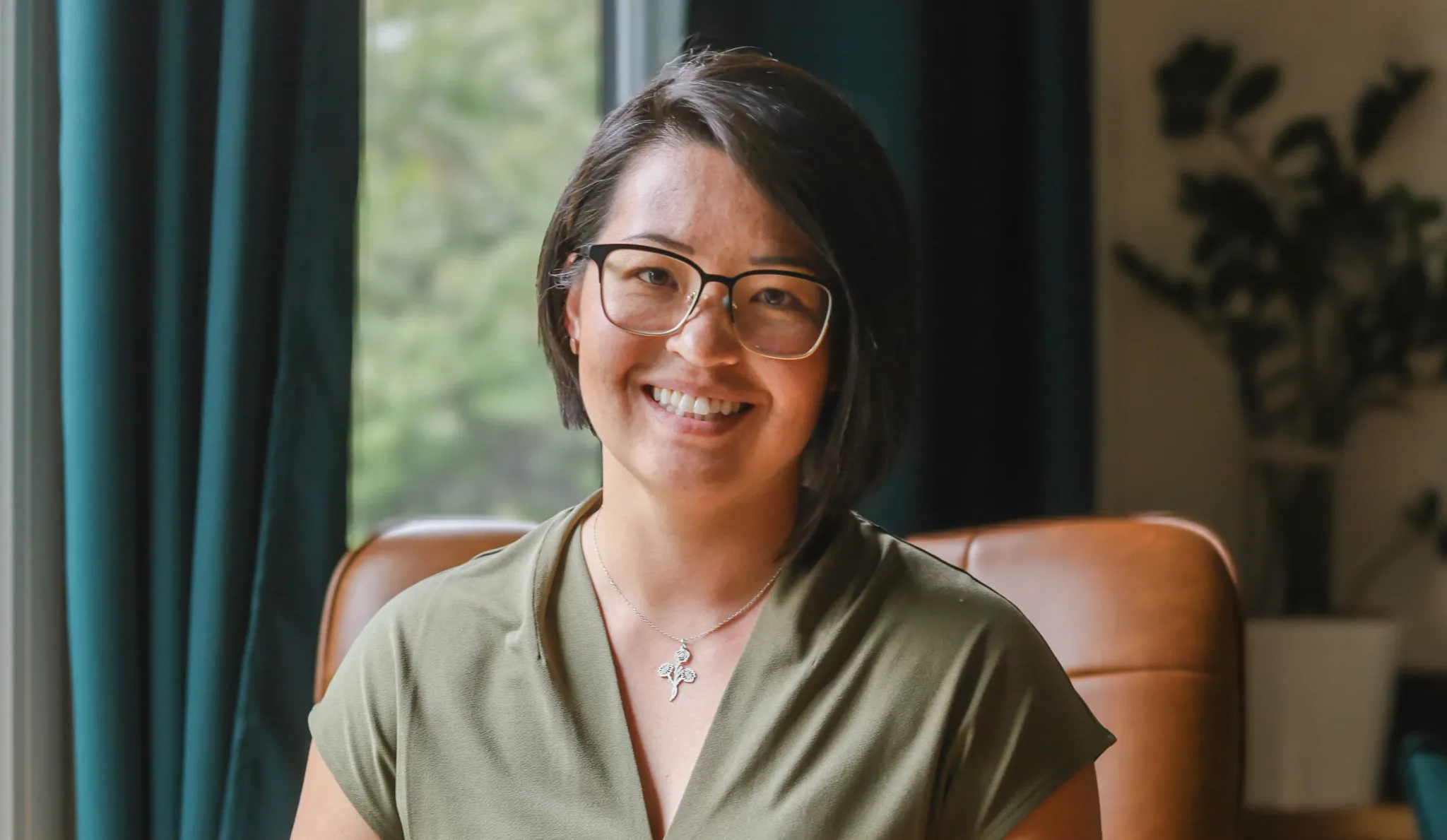 A woman smiling in a cozy interior setting.