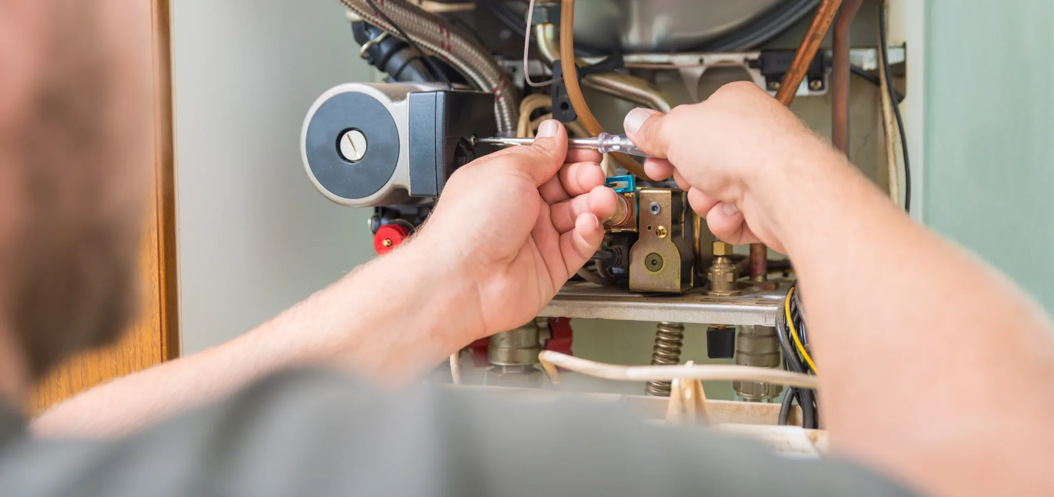 A technician servicing HVAC equipment with tools.