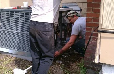 Technicians installing an air conditioning unit outdoors.