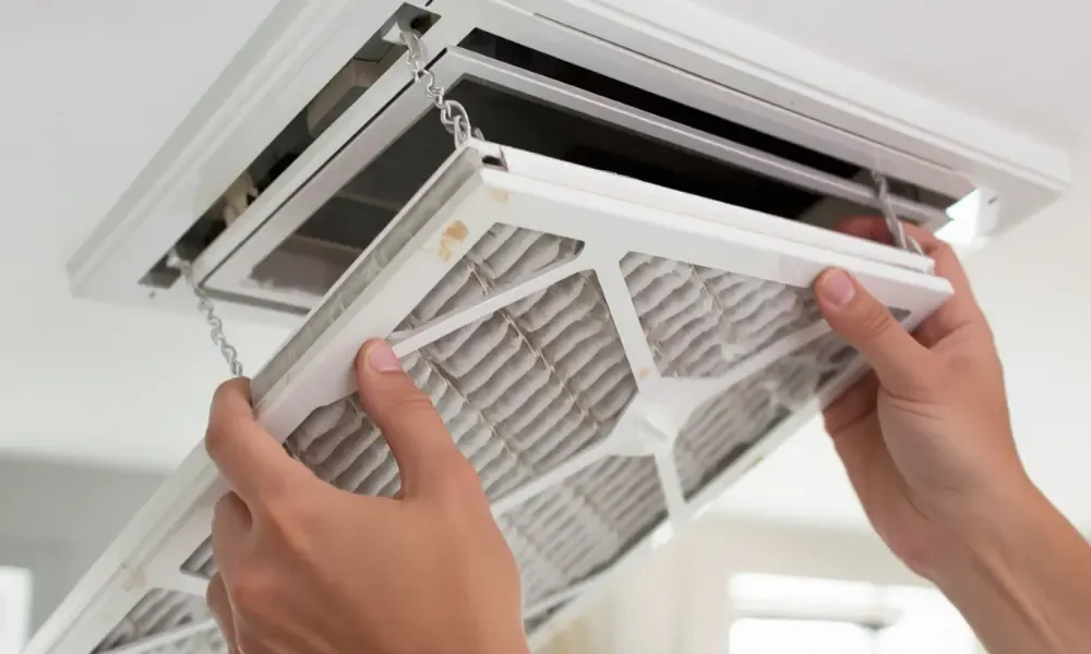 A person removing a dirty air filter from an HVAC unit.