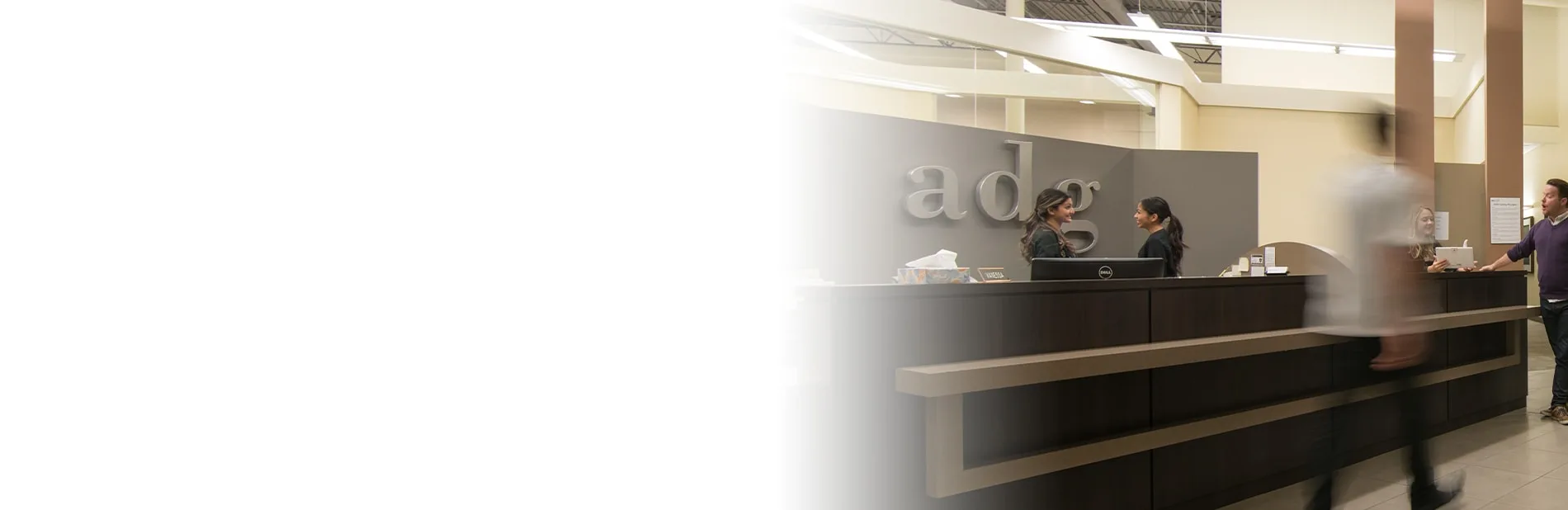 Dental clinic reception area with staff interacting.