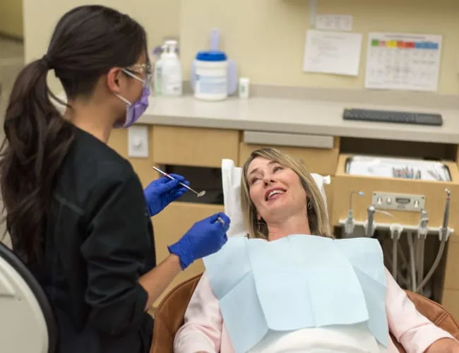 A dentist examines a smiling patient in a dental clinic.
