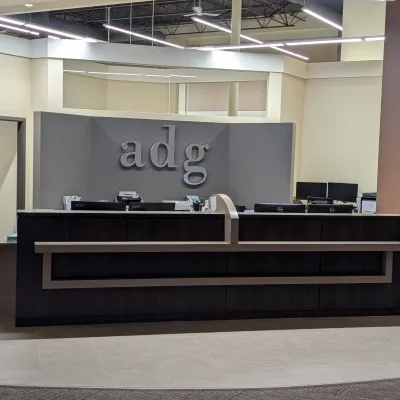 Dental reception area with dark wooden desk and 'adg' sign.
