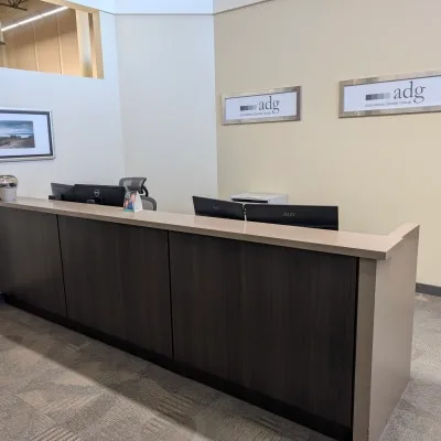 A dental reception area with a dark wood front desk and computers.