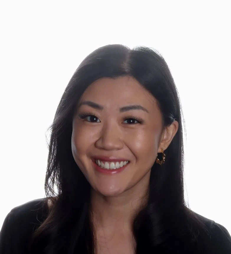 A smiling woman with long black hair and earrings.