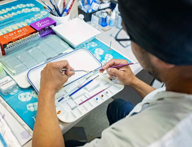 A dental professional preparing tools in a clinic setting.