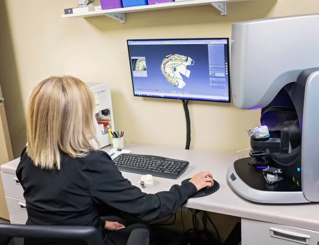 Dental assistant using a computer to view a dental model.