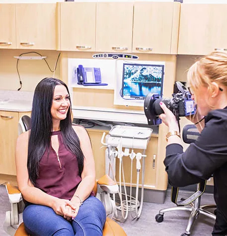 A woman smiling in a dental office while being photographed.