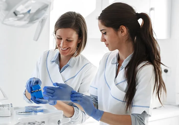 Two dental professionals preparing instruments in a clinic.
