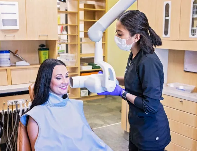 A dental hygienist taking an x-ray of a patient in a clinic.