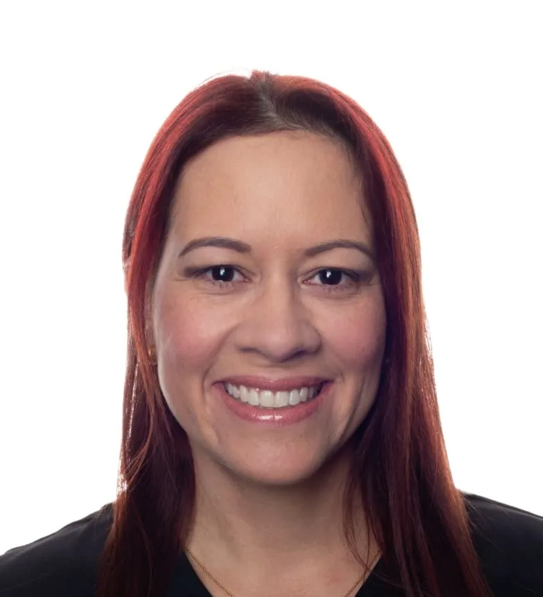 A smiling woman with red hair in a black top.